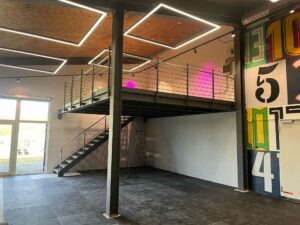 Maßgefertigte Esstische aus Metall und Holz 1 Eine Stahlbühne mit Holzboden für ein Fitnesstudio. Es entsteht so mehr Platz in der hohen Halle.